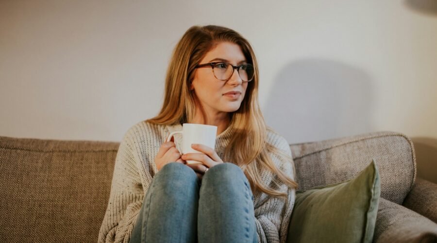 woman in blue denim jeans sitting on gray sofa