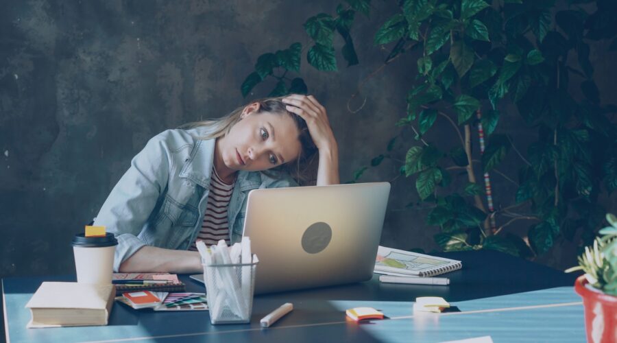 A woman appears stressed while working on laptop.