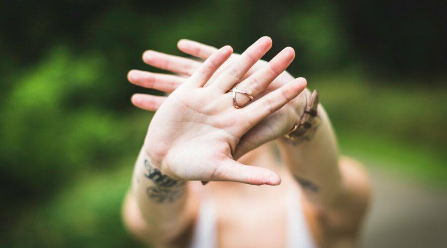 selective focus photo of person's hand with gold-colored ring in it