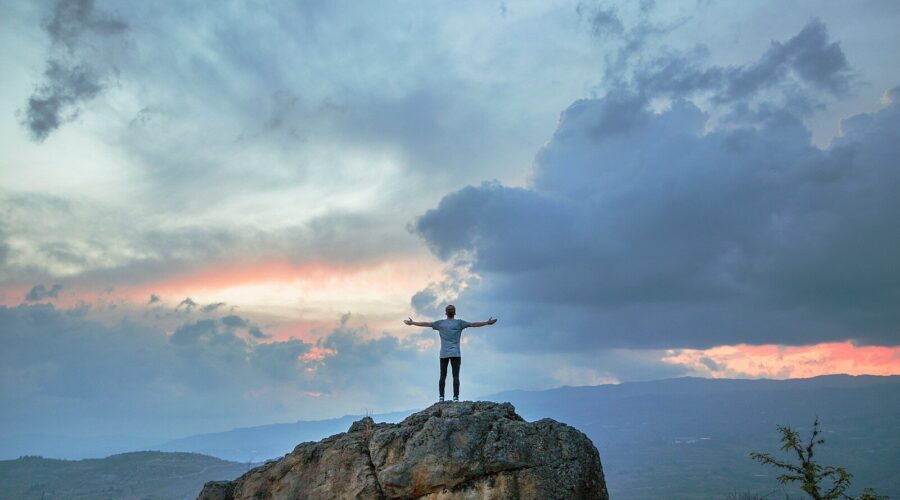 man standing on top of rock mountain during golden hour