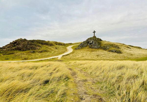A grassy hill with a cross on top of it