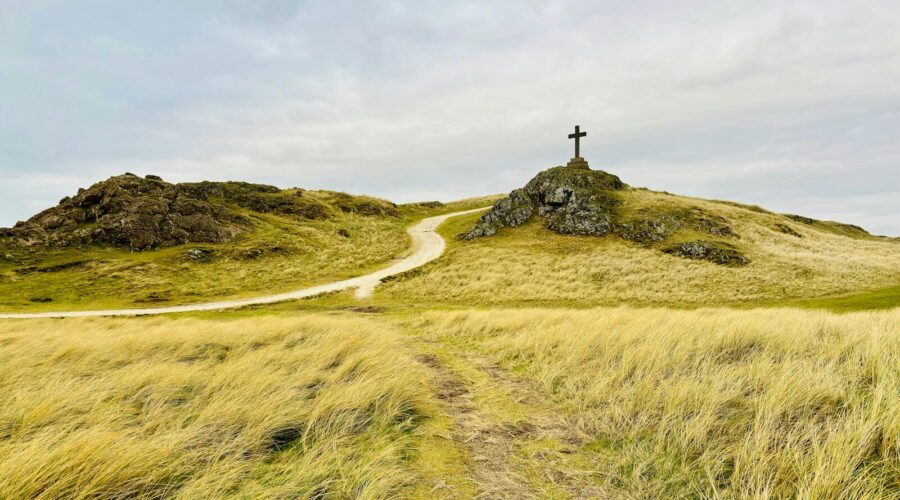 A grassy hill with a cross on top of it