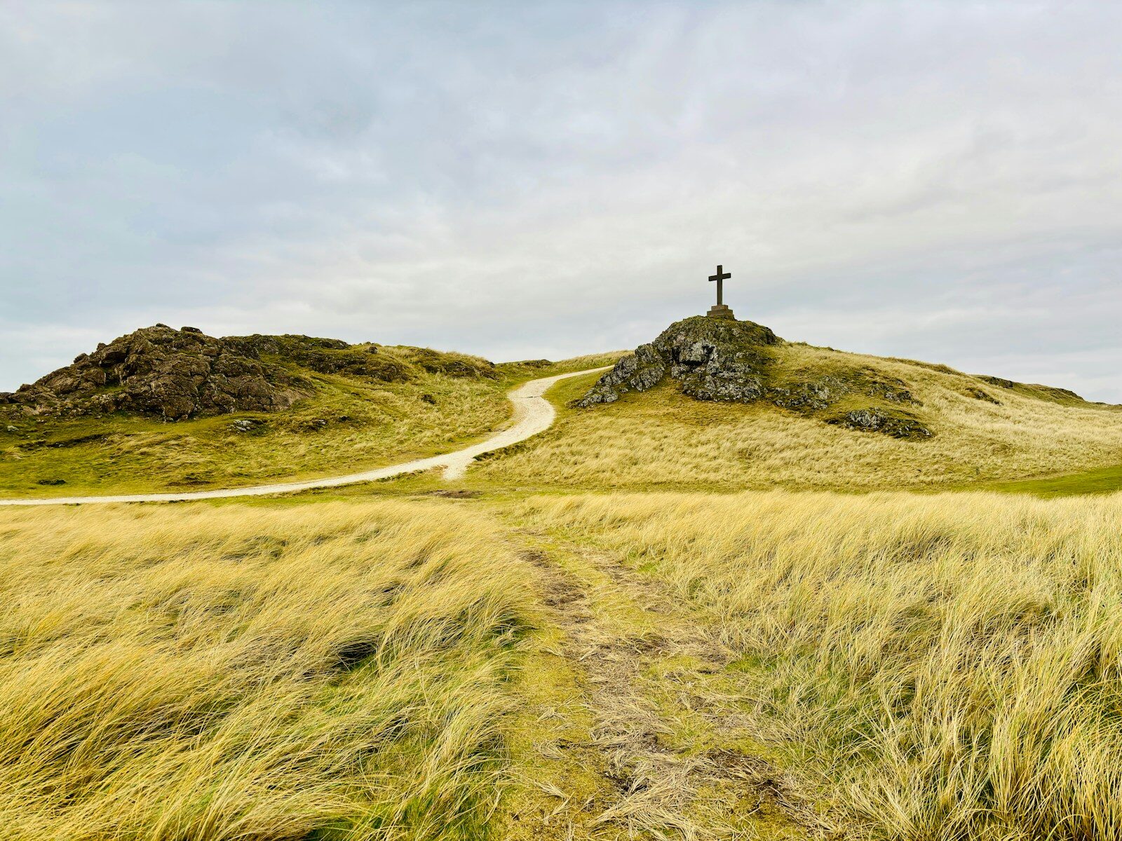 A grassy hill with a cross on top of it