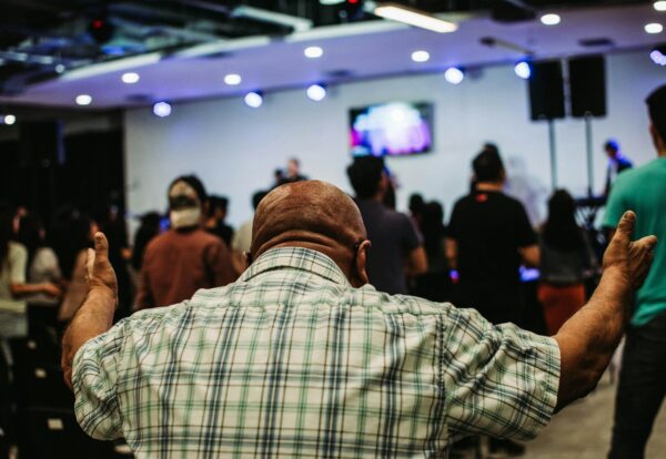 man wearing green and black plaid sport shirt while raising hand