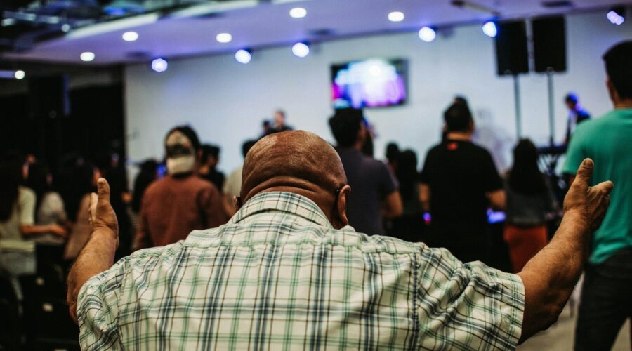 man wearing green and black plaid sport shirt while raising hand