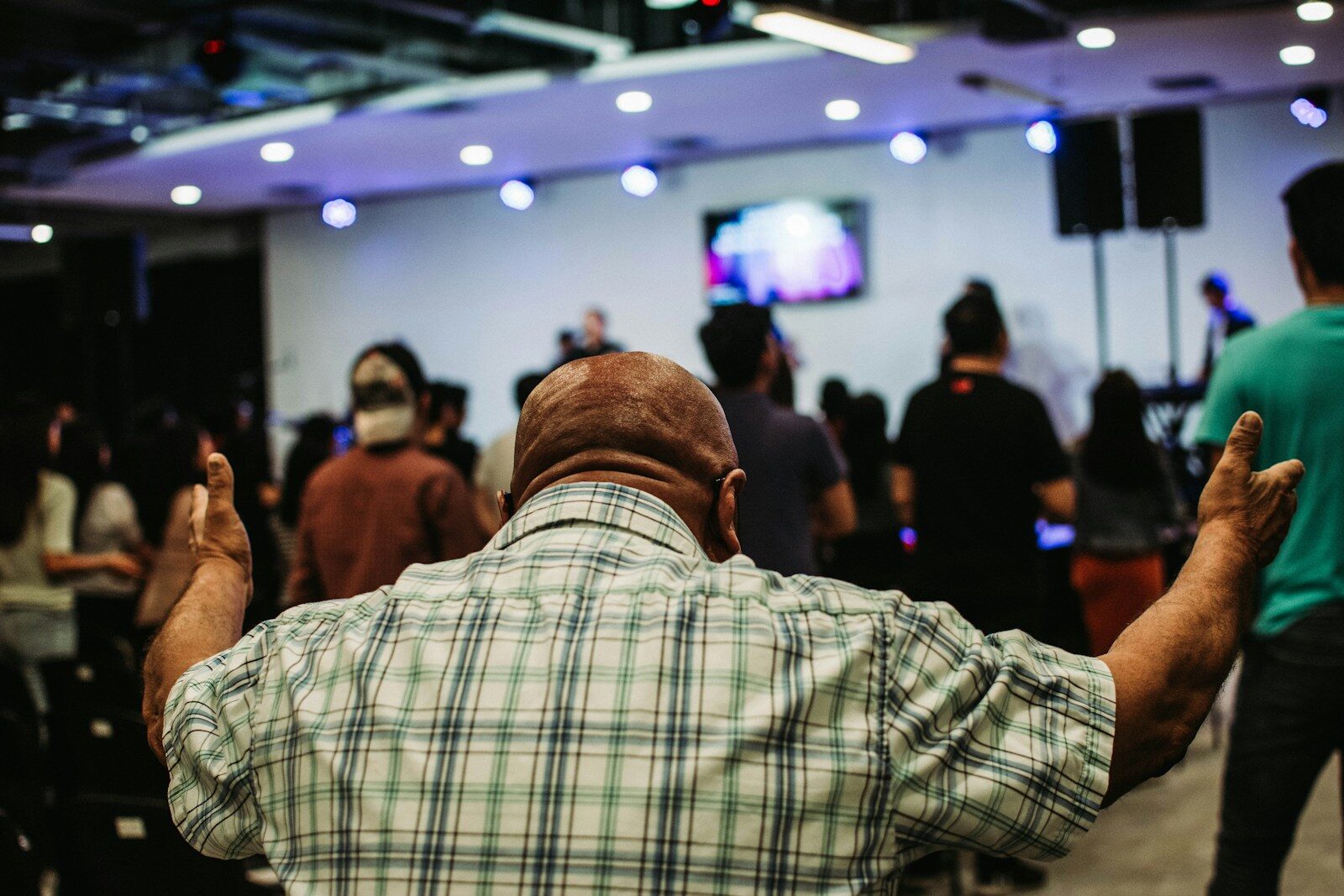 man wearing green and black plaid sport shirt while raising hand