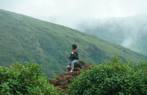 Person sitting on rocks overlooking misty mountains