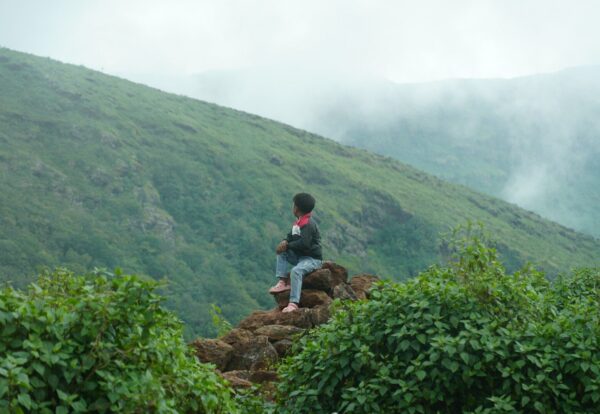 Photo by Abhisek Tripathy Person sitting on rocks overlooking misty mountains