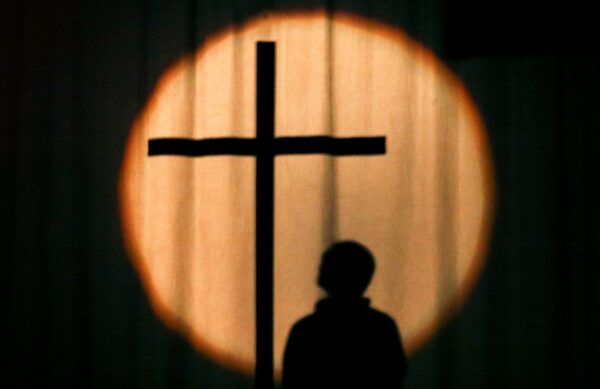 a silhouette of a person standing in front of a cross