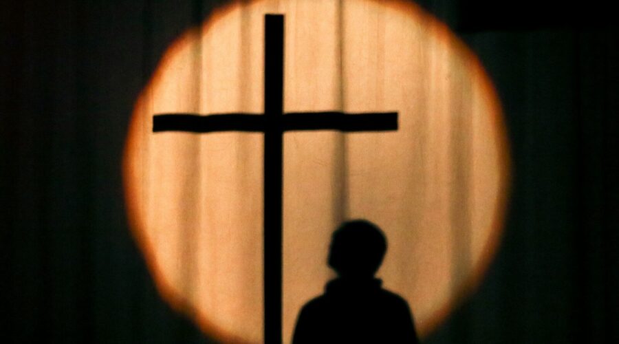 a silhouette of a person standing in front of a cross